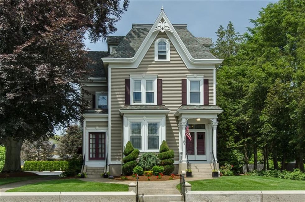 House with gray siding, maroon shutters, and a front porch surrounded by trees