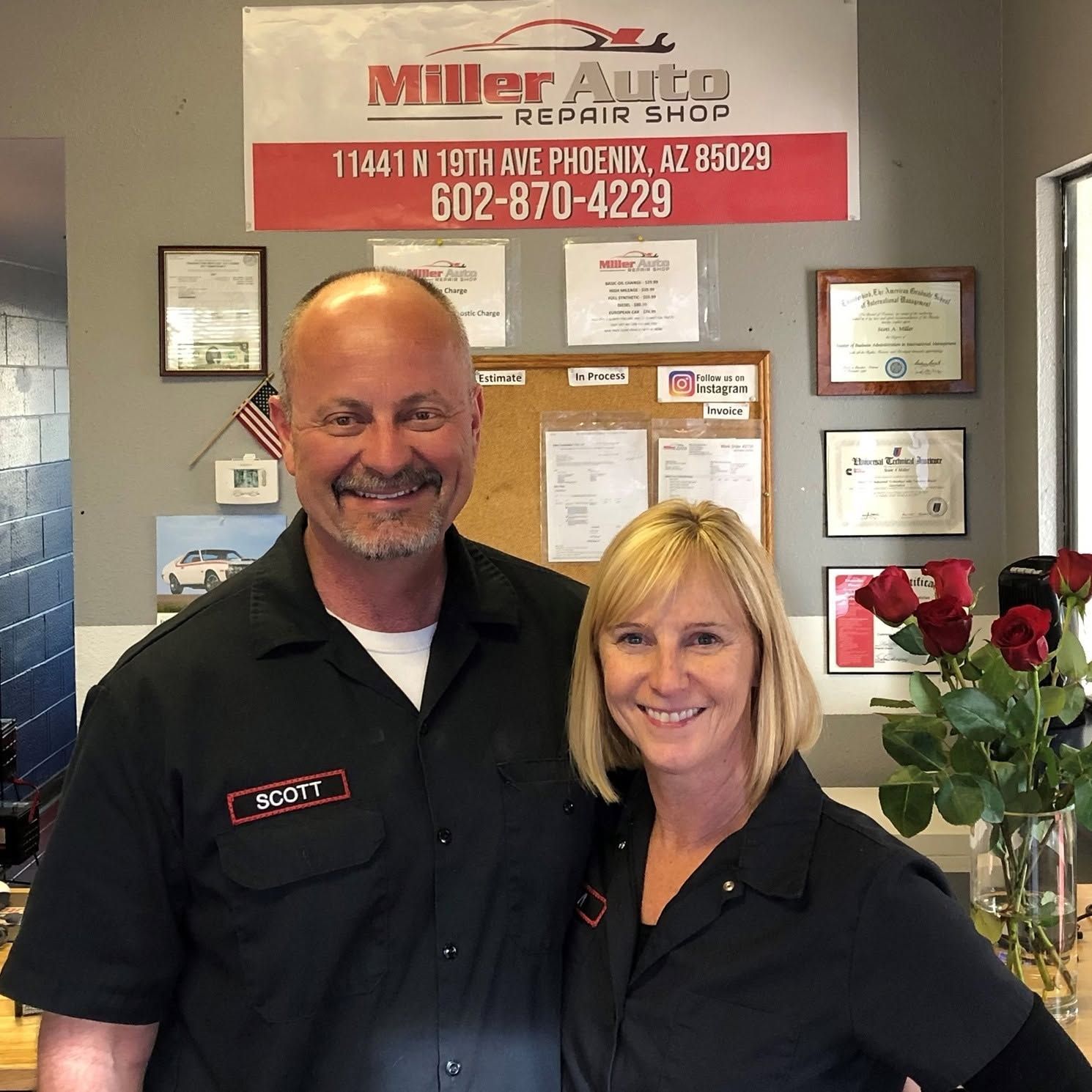 Two smiling staff members in black uniforms | Miller Auto Repair Shop