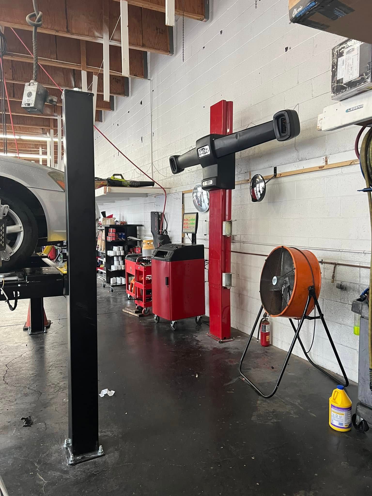 Auto repair shop interior with a car lift, tools, and a large orange fan on the floor | Miller Auto Repair Shop