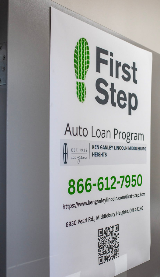 First Step Auto Loan Program sign on office door, with green and black text and QR code.