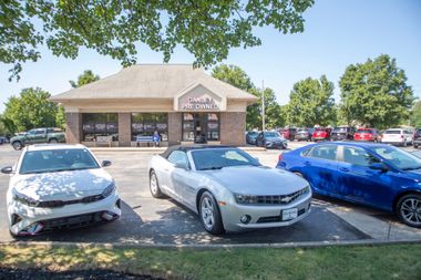 Three parked cars in front of a small brick building on a sunny day