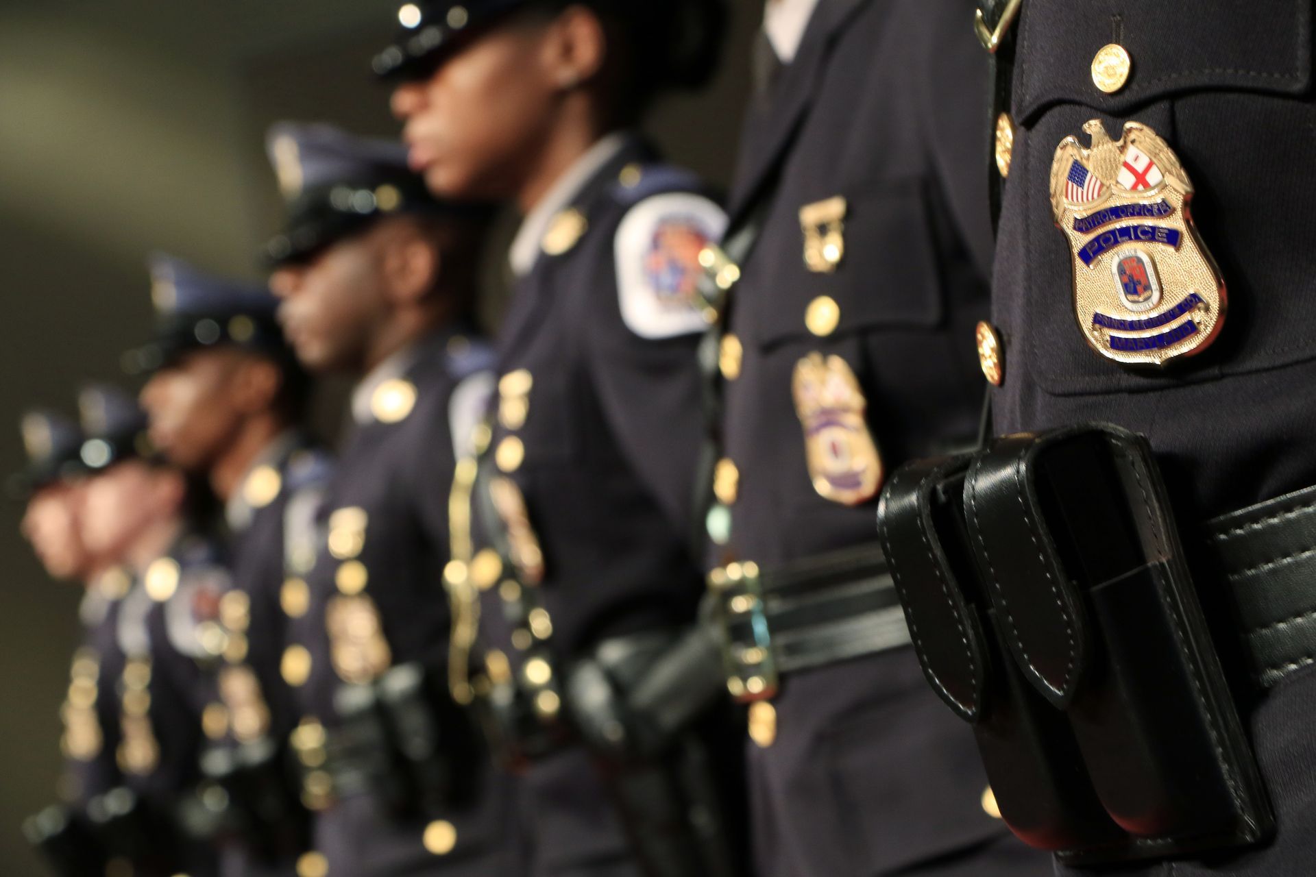 Police officers standing in a row at a formal ceremony, wearing dark uniforms and badges