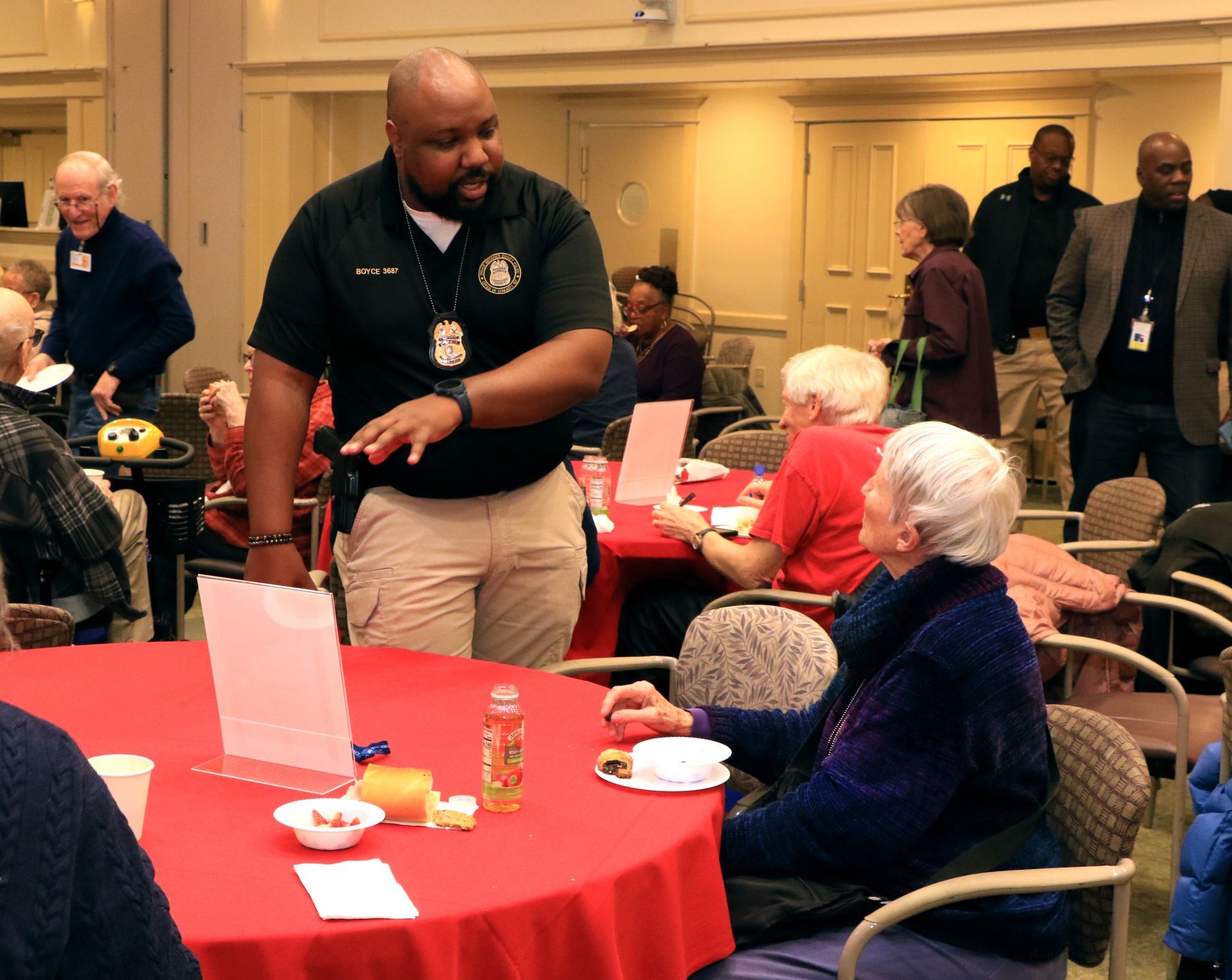 Man serving at a banquet table with red tablecloths in a crowded conference room