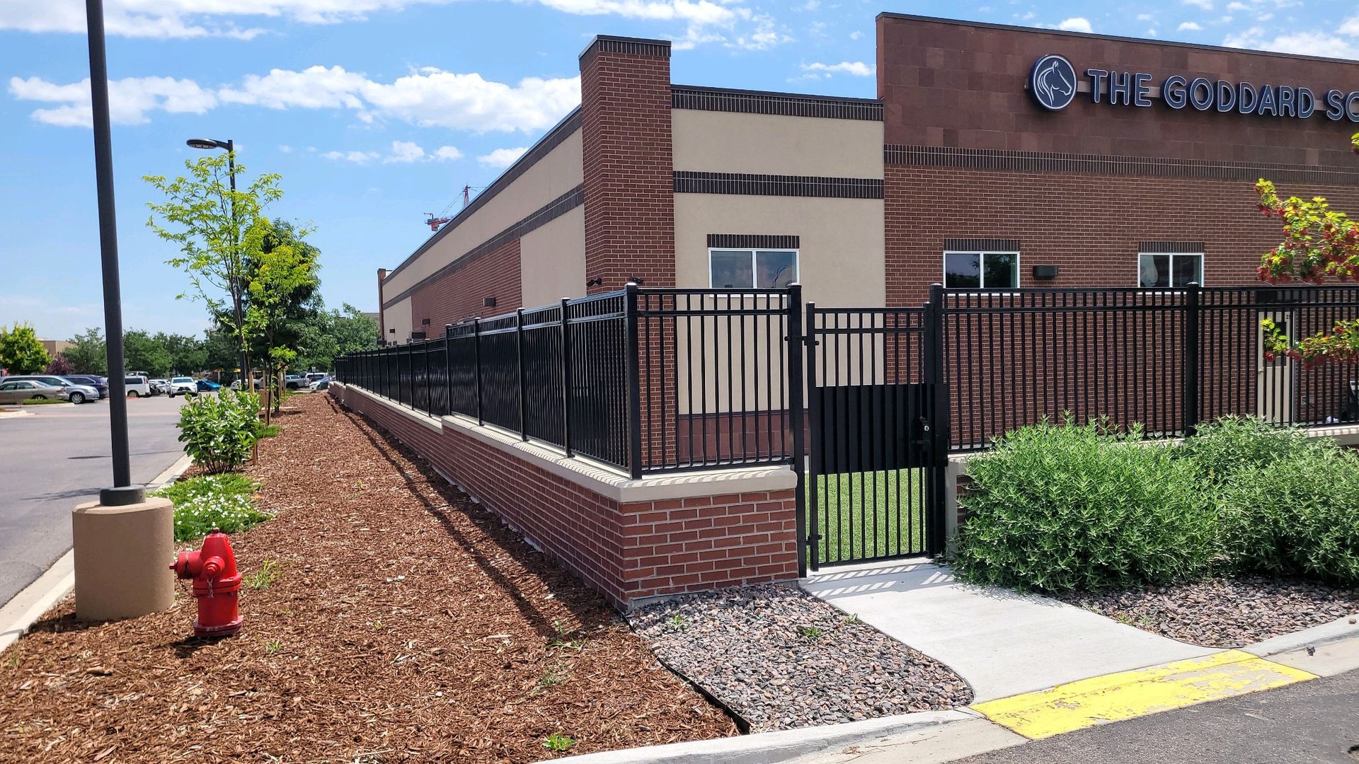 A fire hydrant is in front ornamental iron built by Greater Western Fenceof a brick building