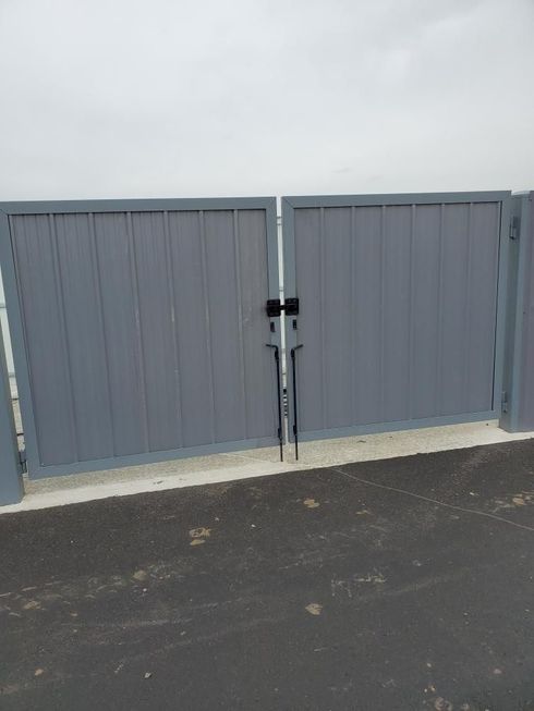A gray gate is sitting on the side of a road.