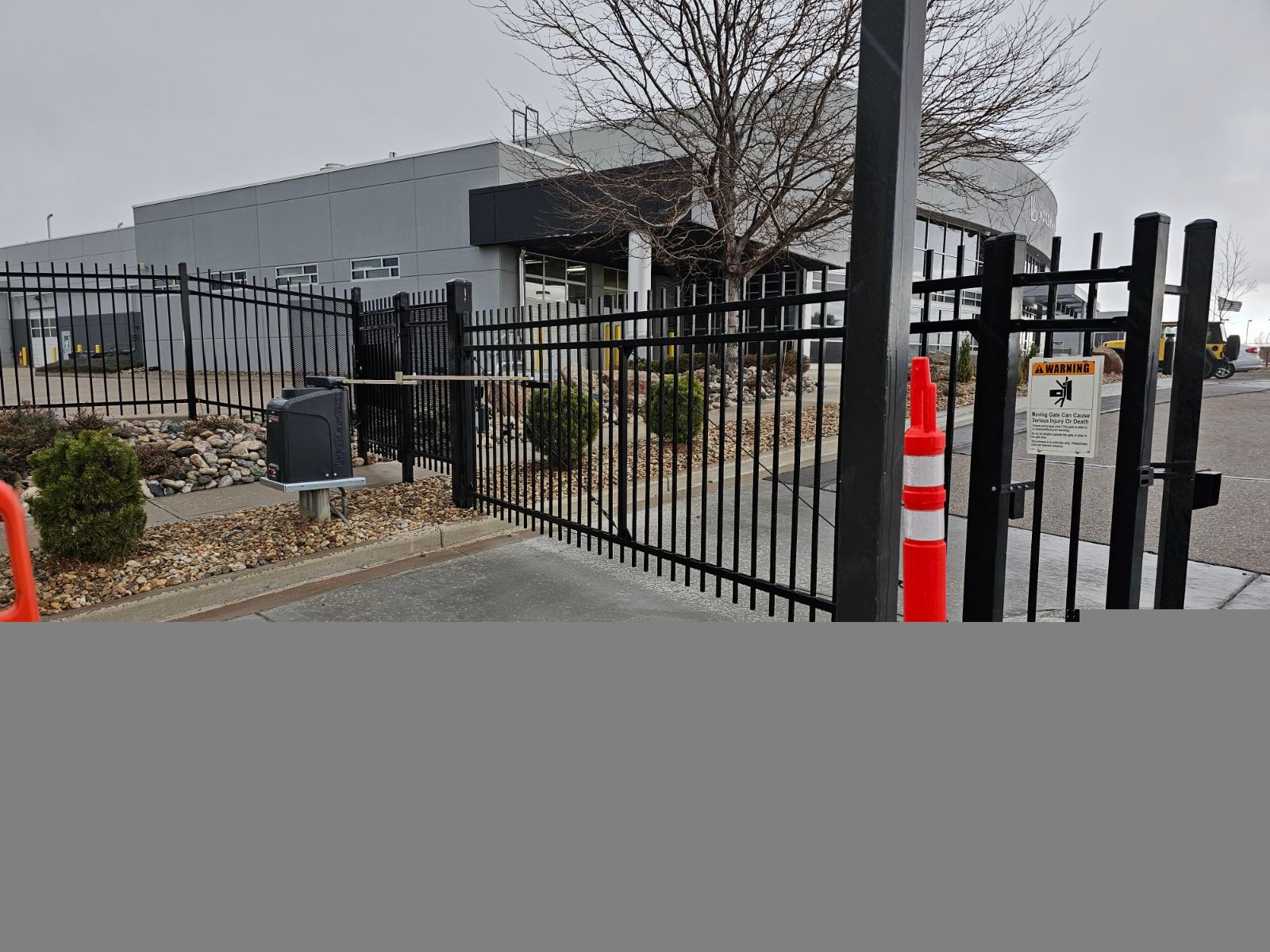 A black metal fence built by Greater Western Fence with a red and white cone in front of a building.