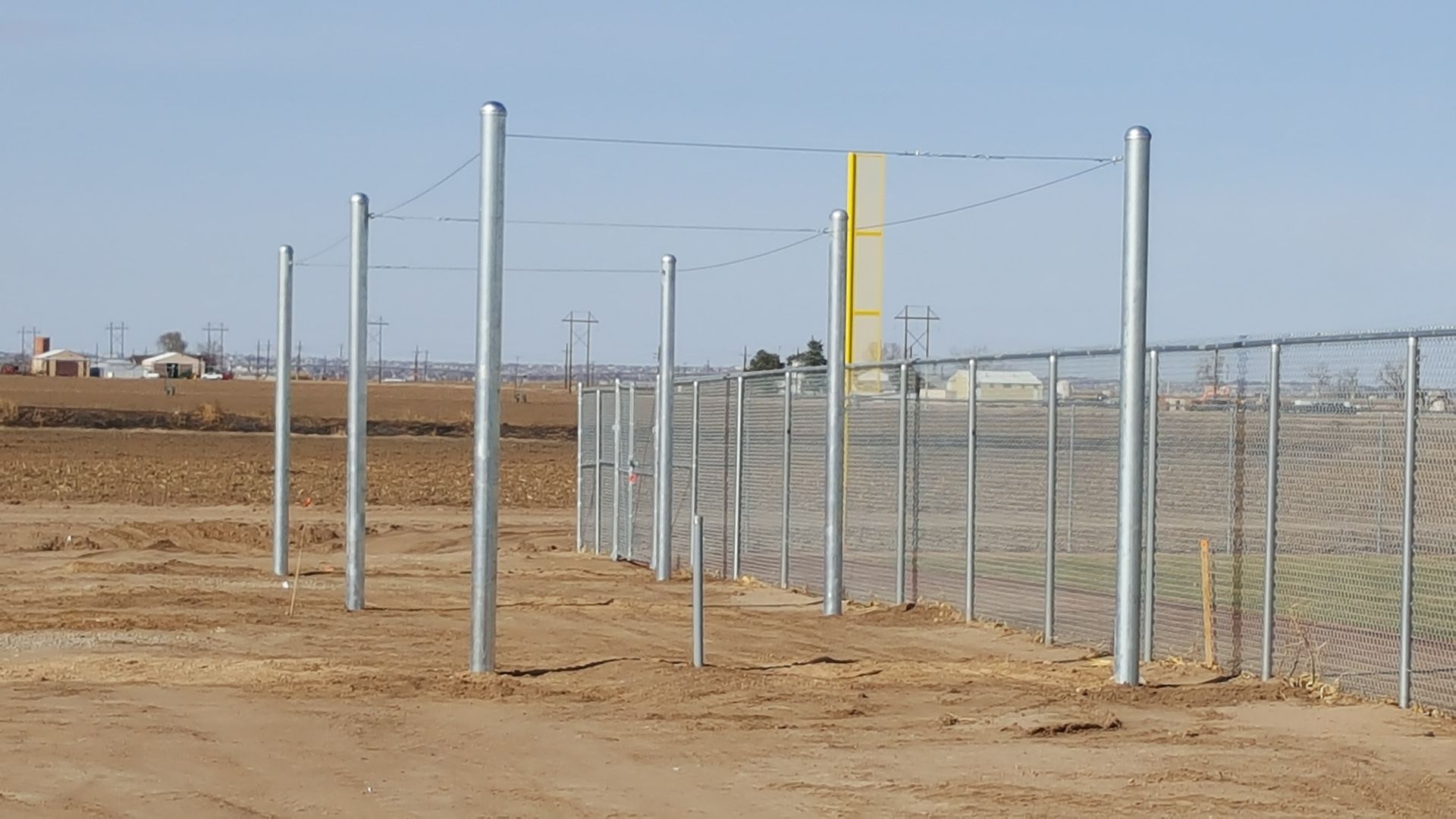 A fence is being built by Greater Western Fencein the middle of a dirt field.
