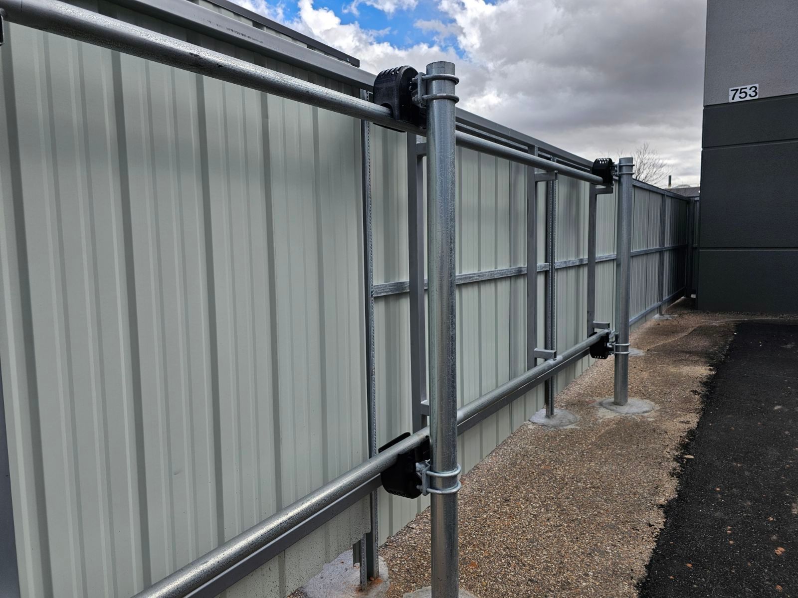 A metal fence built by Greater Western Fence is sitting next to a building.