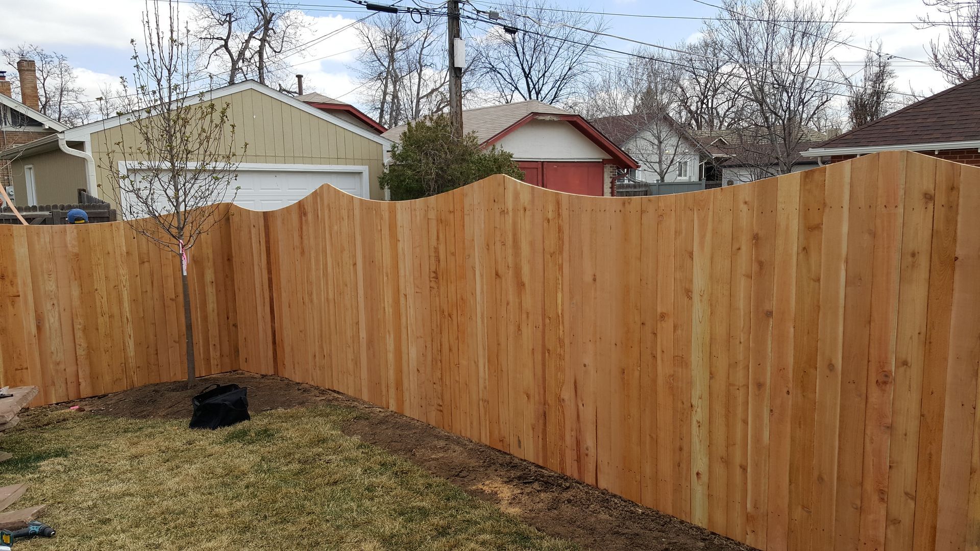 A wooden fence is in the backyard of a house.