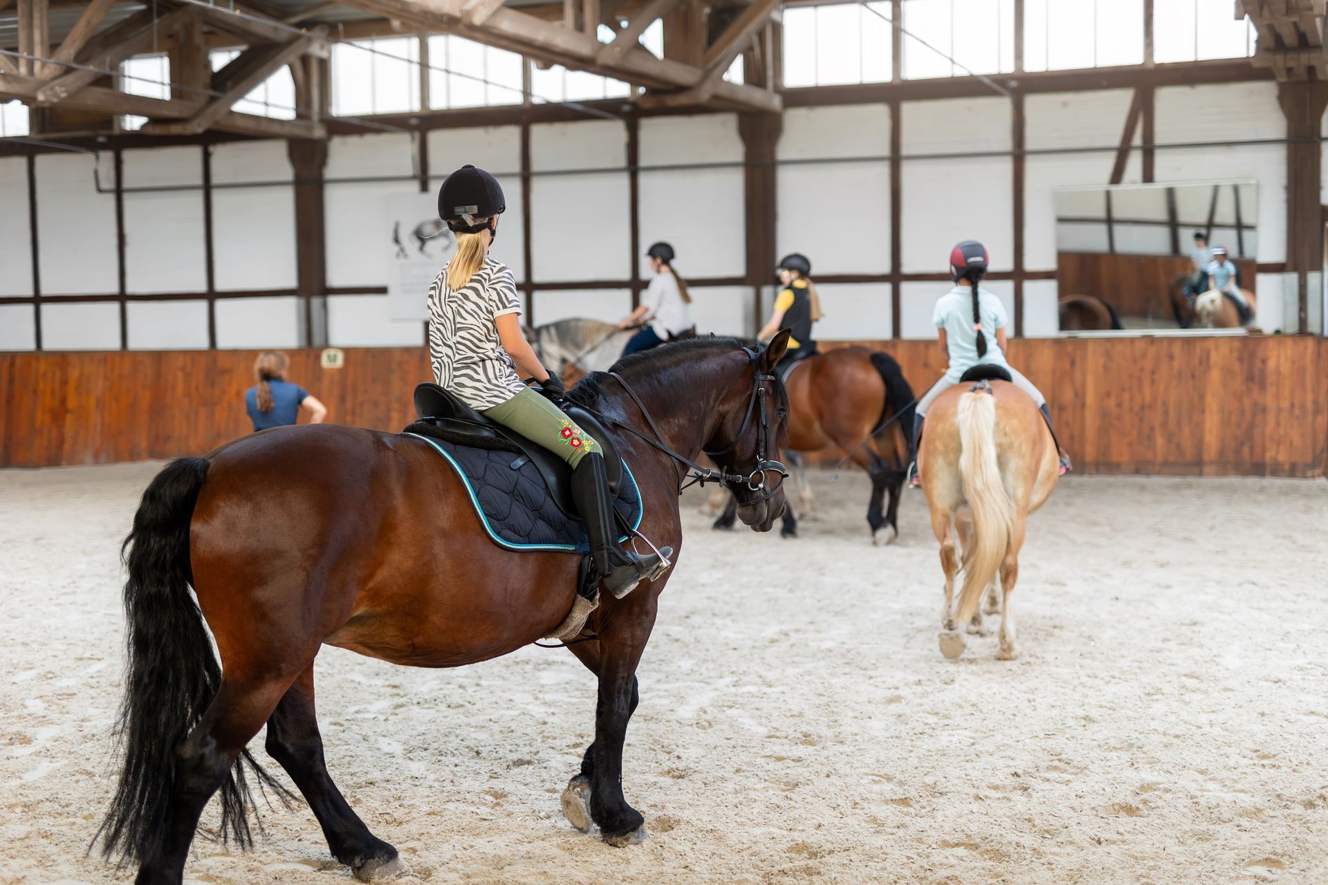 A group of people are riding horses in an indoor arena.
