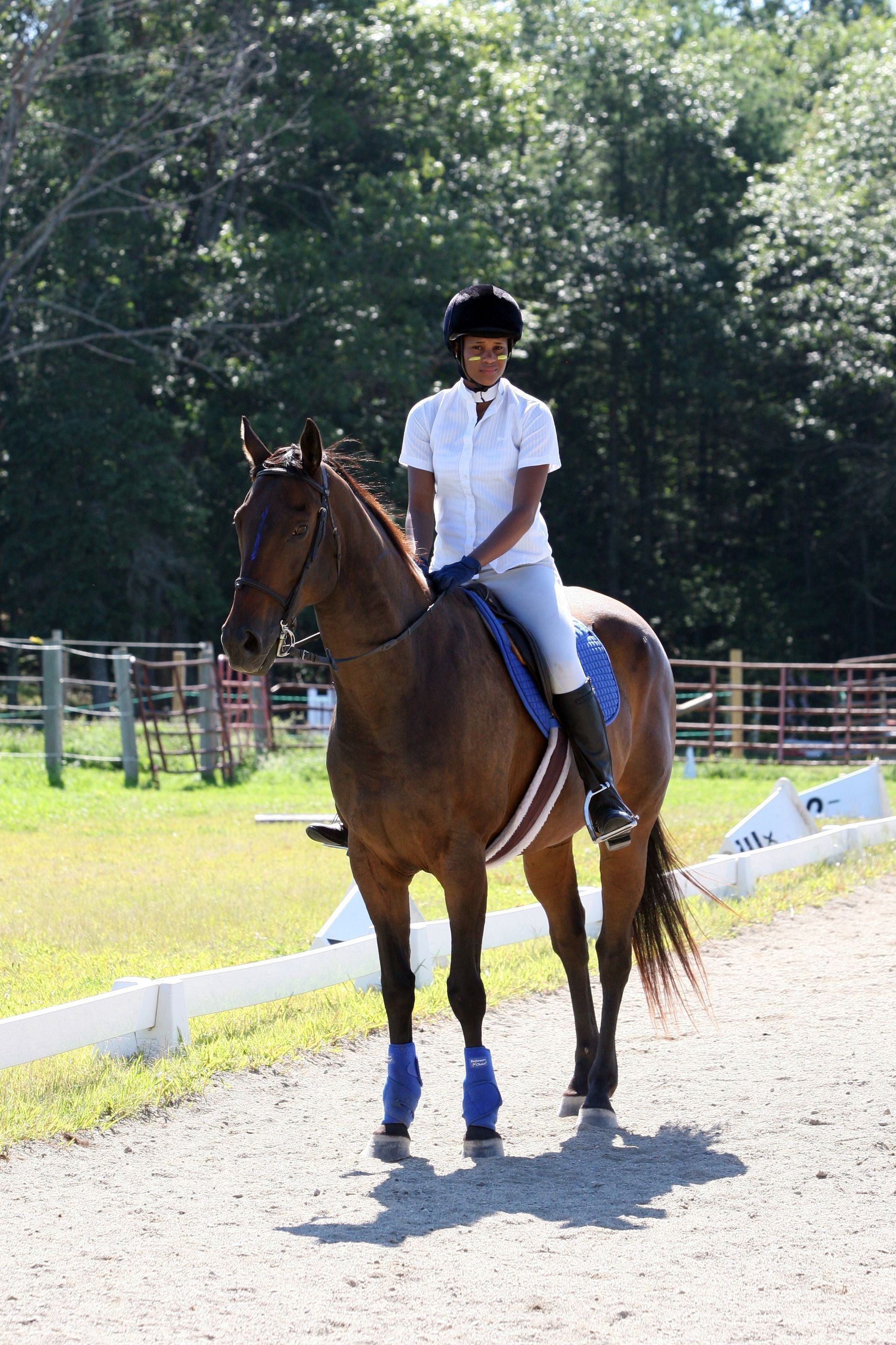 A person is riding a brown horse on a dirt road