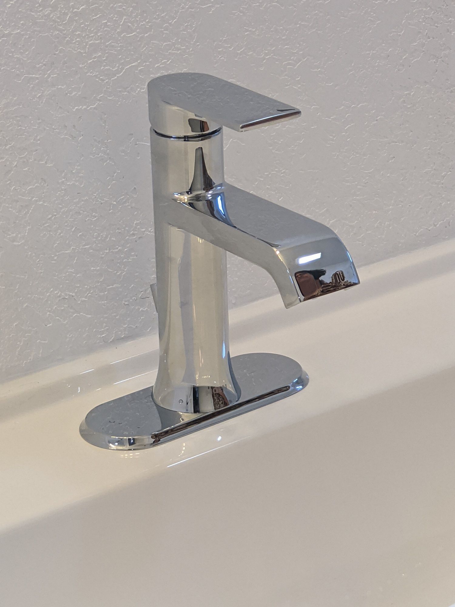 A chrome faucet is sitting on top of a white sink.