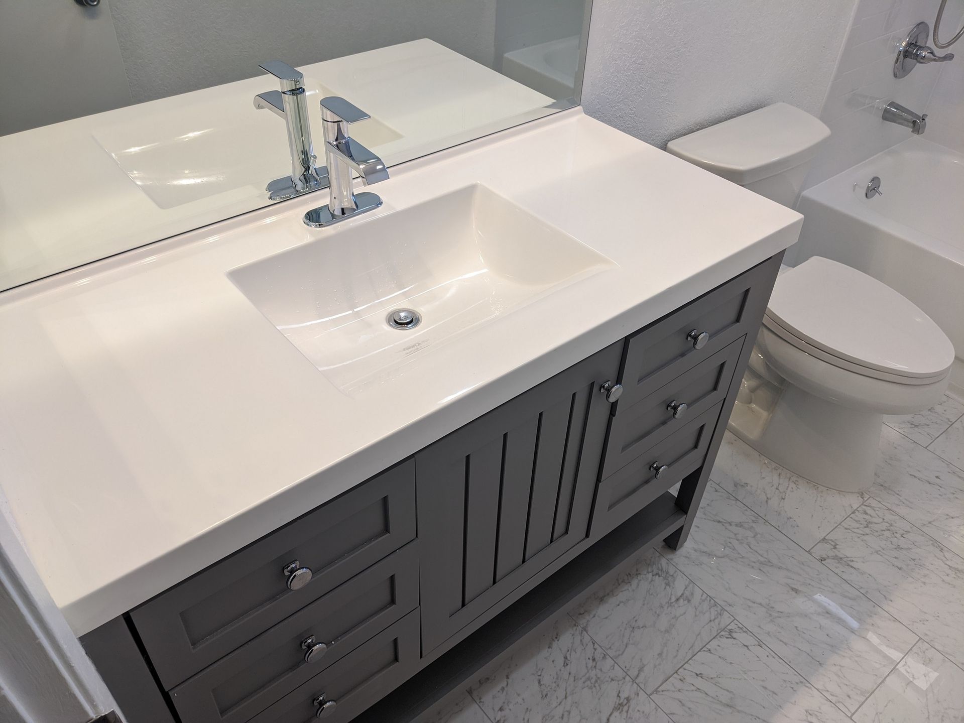 A bathroom with a sink , toilet , tub and mirror.