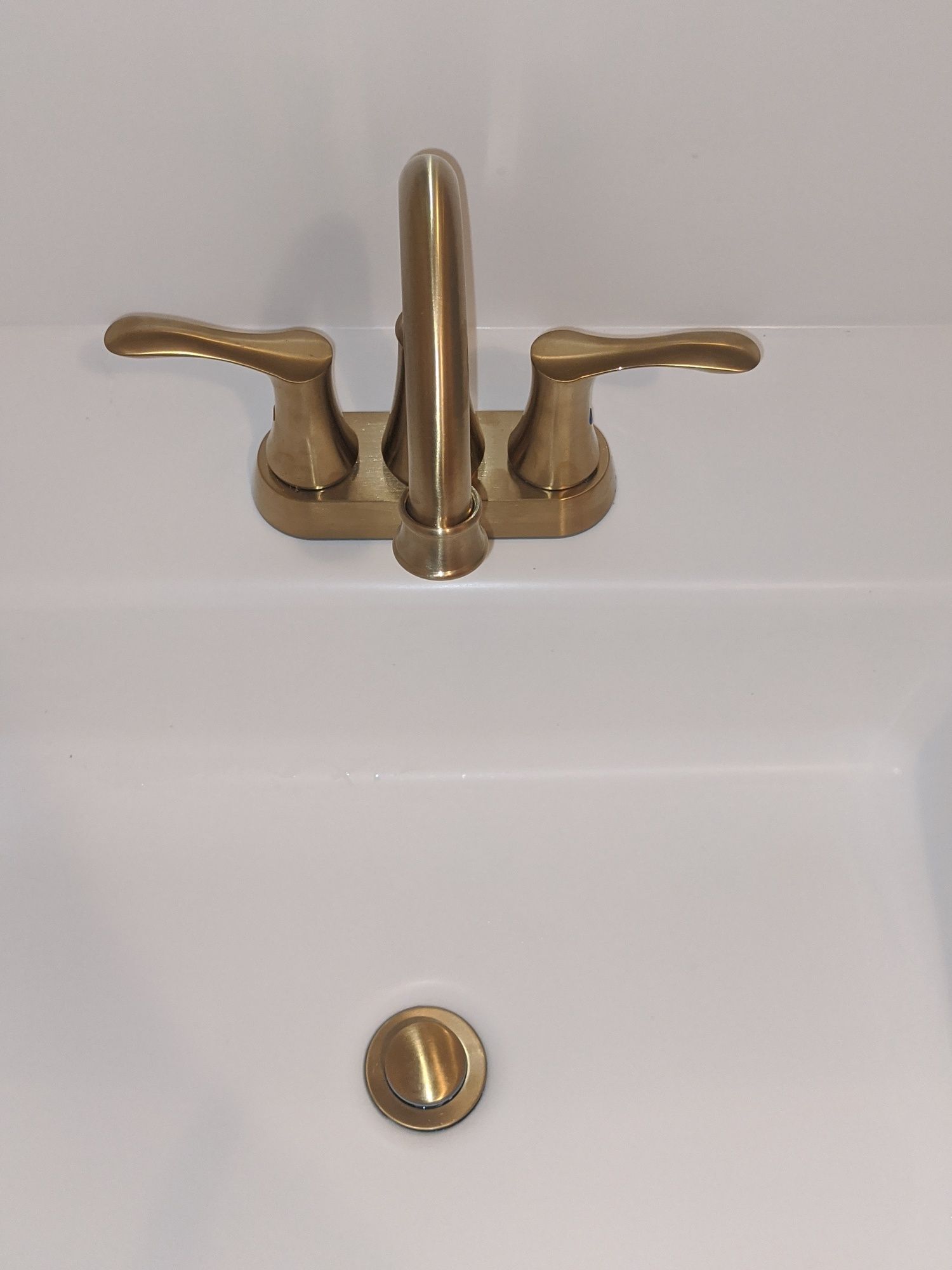 A bathroom sink with a brass faucet and a drain
