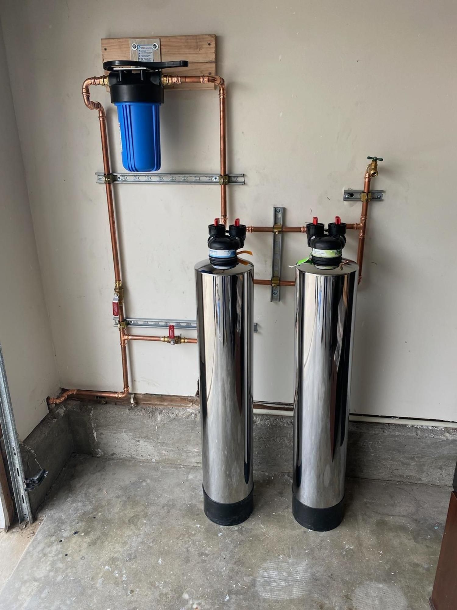 Two stainless steel water filters are sitting next to each other in a room.