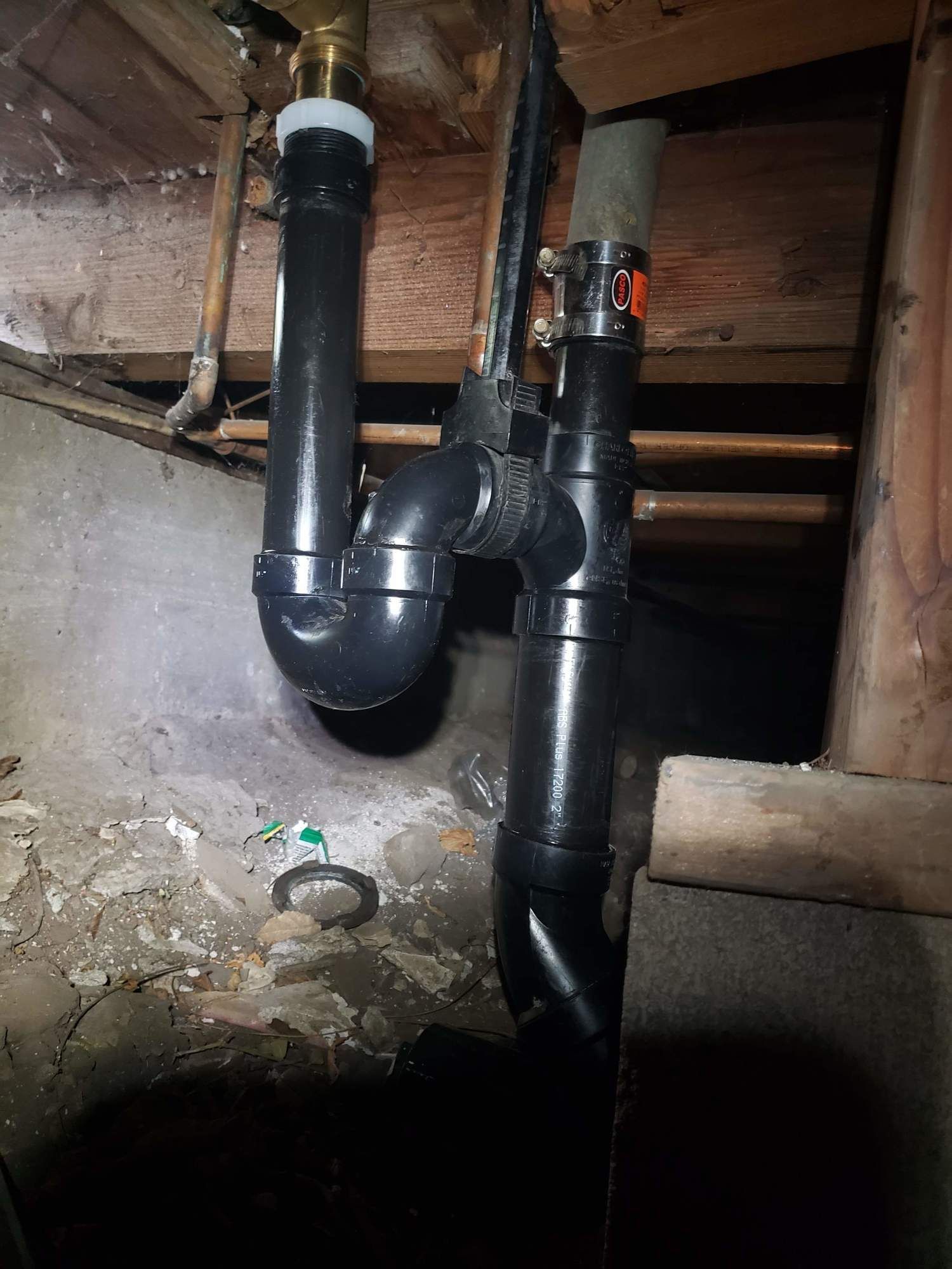 A black pipe is hanging from the ceiling of a basement.