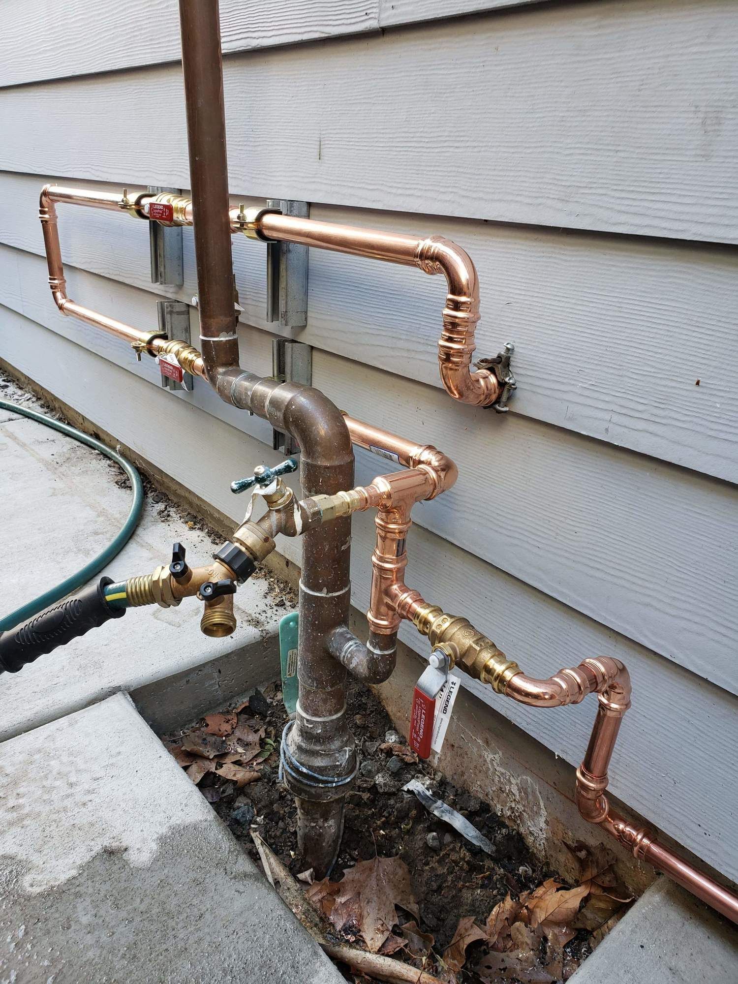 Copper pipes are being installed on the side of a house.