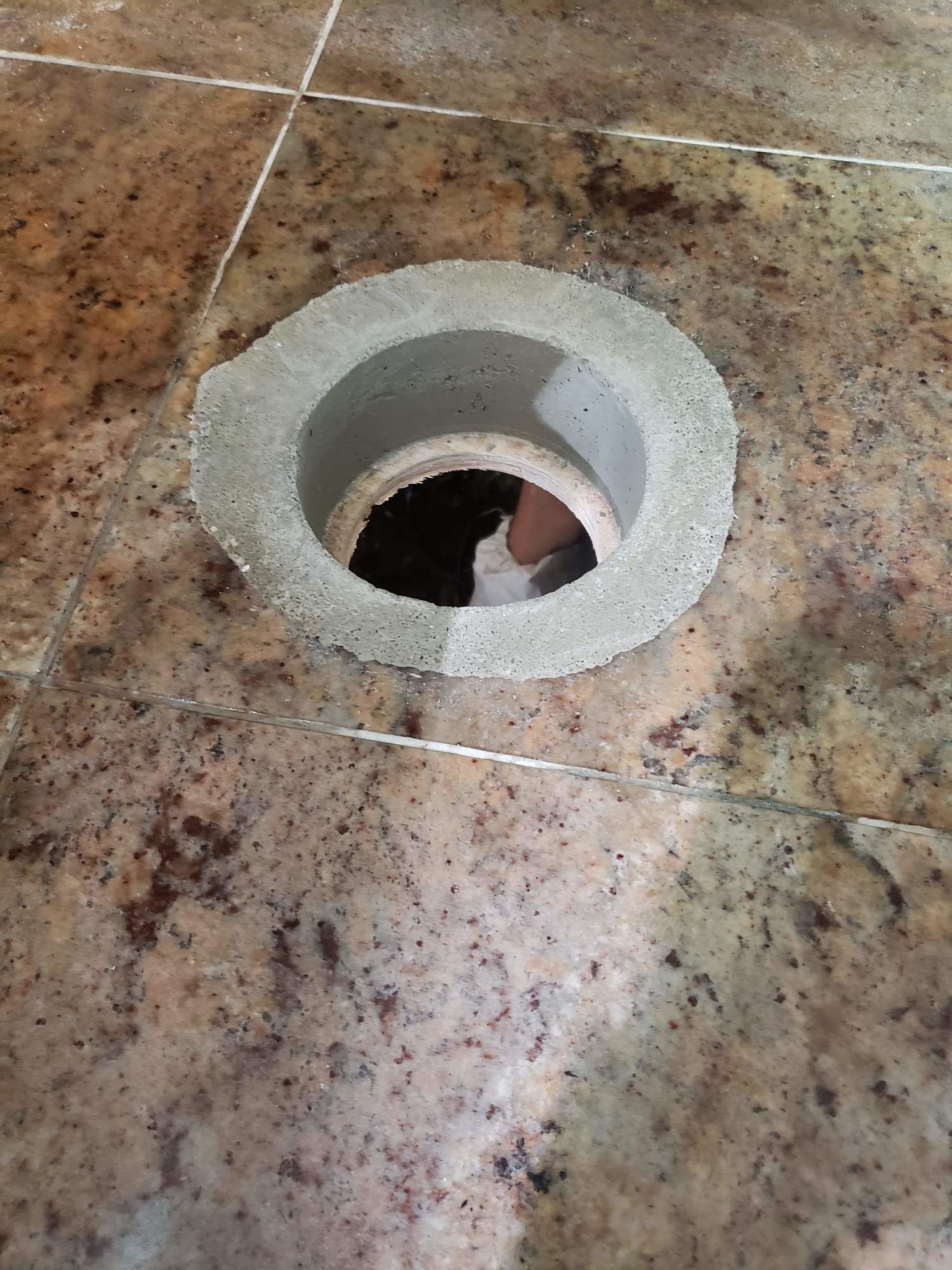 A person is standing in a hole in a tiled floor.