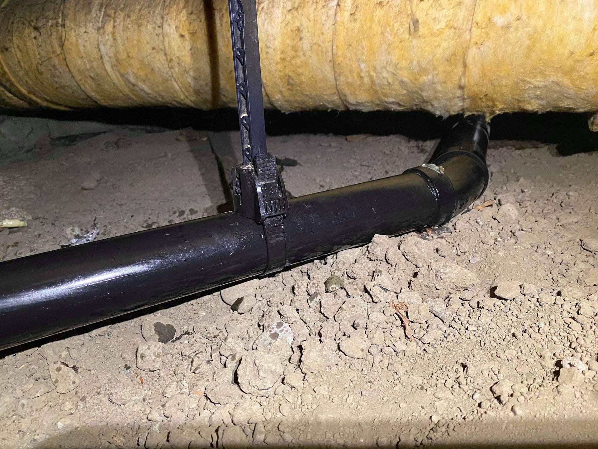 A black pipe is sitting on top of a pile of dirt.