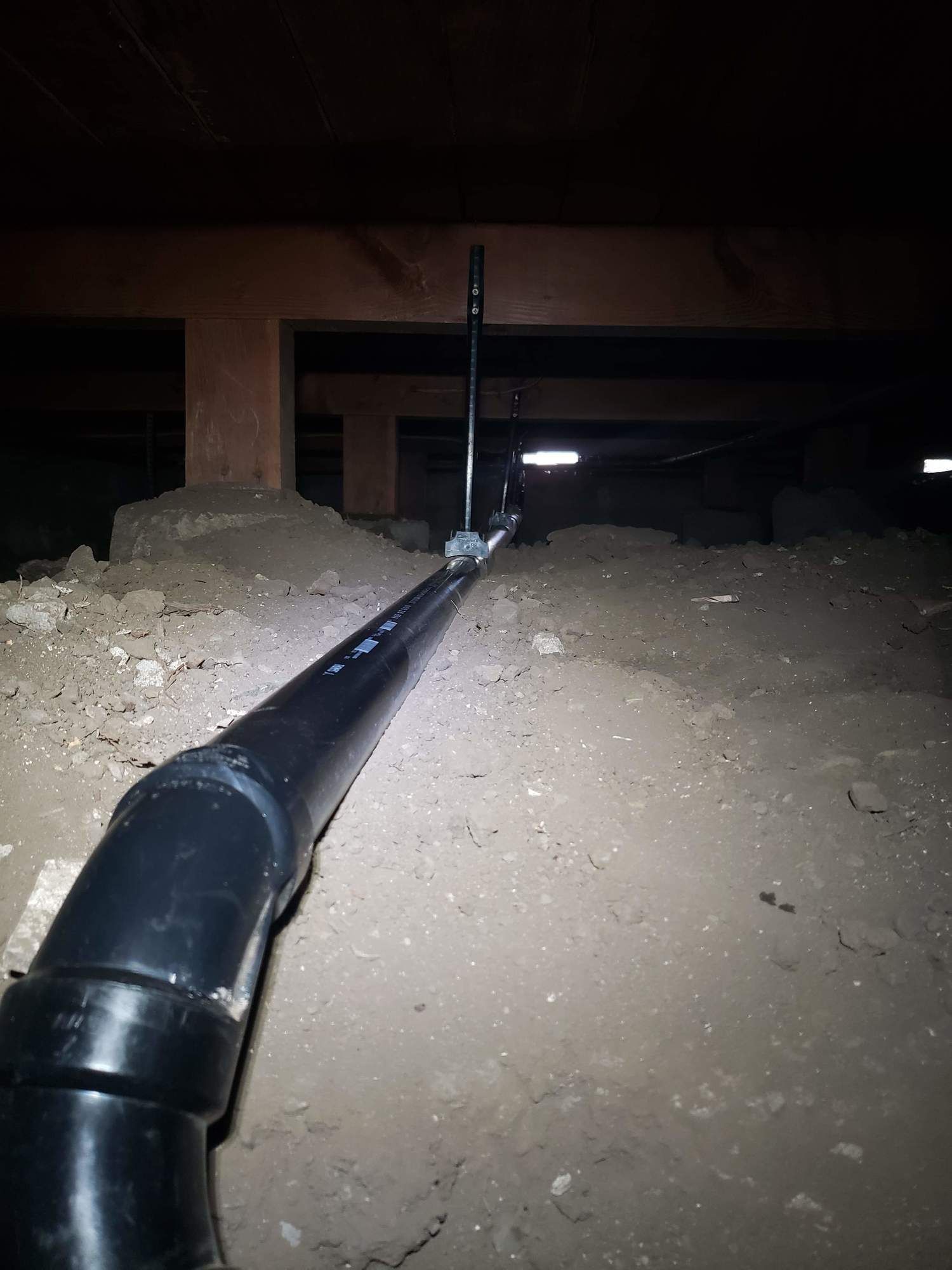 A black pipe is hanging from the ceiling in a dark room.