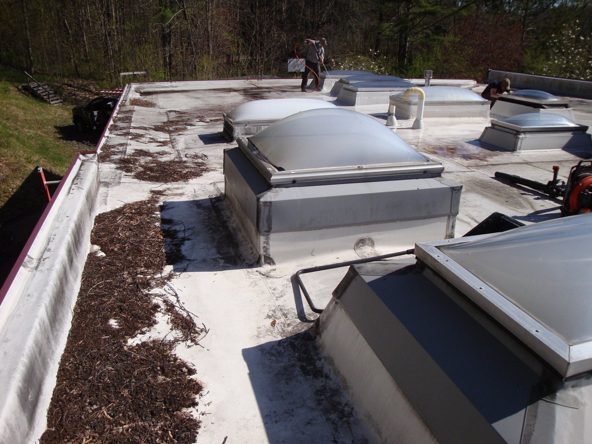 A Rodd Roofing employee performing routine maintenance on a commercial flat roof in Vermont