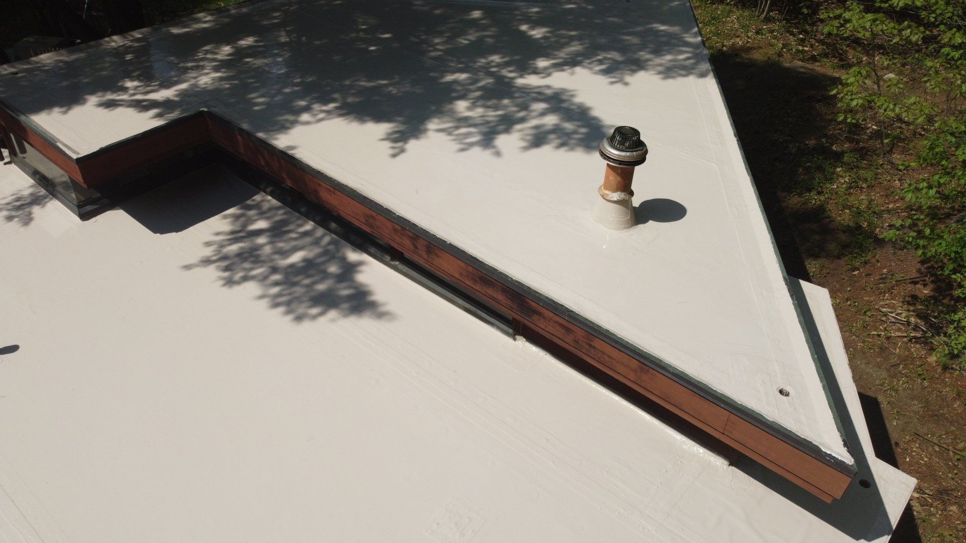 An aerial view of a white roof with a chimney on it.