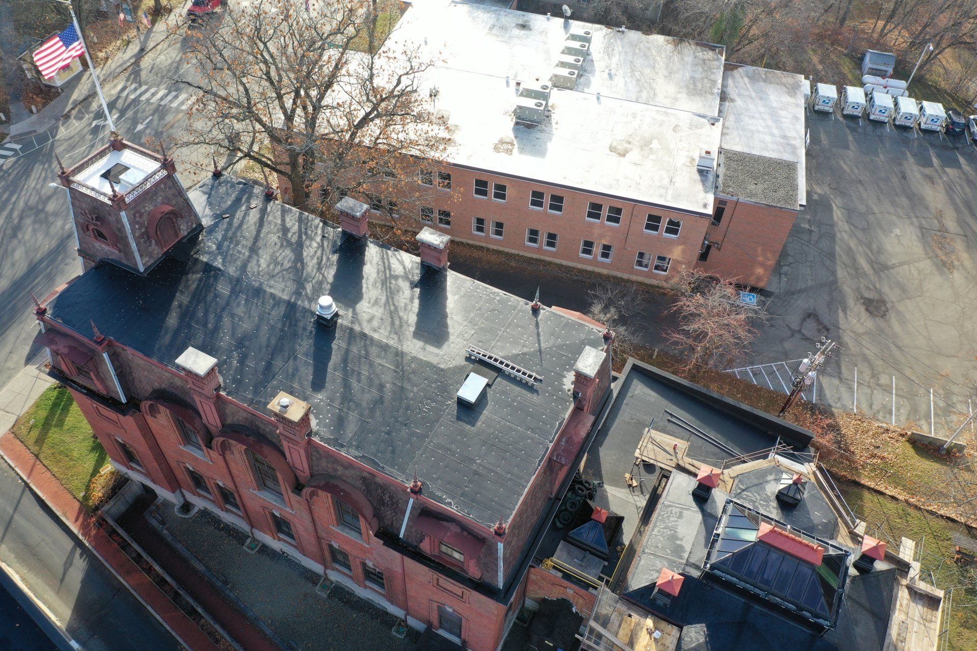 Aerial view of red-brick buildings with slate roofs and a parking lot on a sunny day