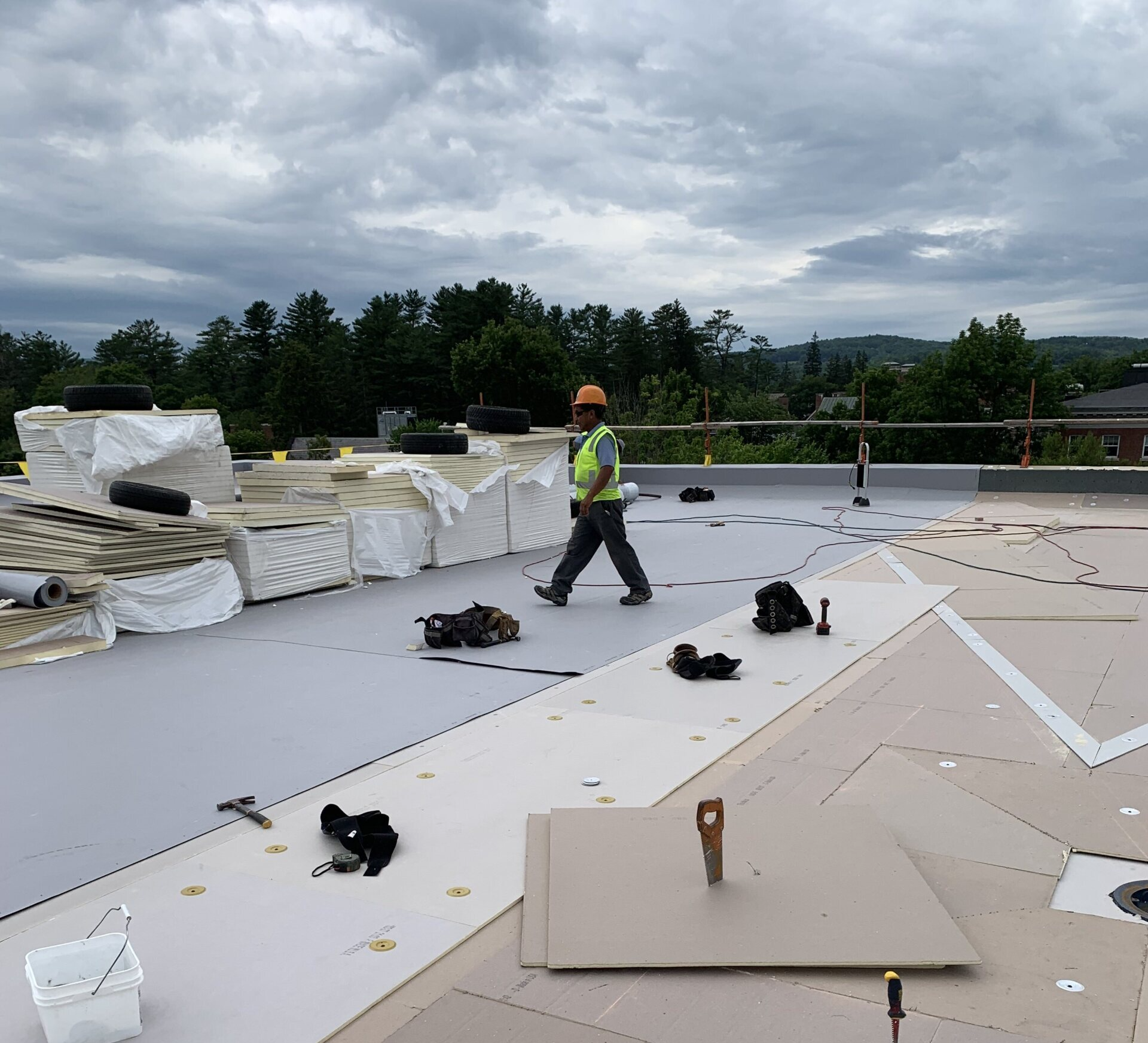 A Rodd Roofing expert on a commercial roof surrounded by roofing supplies in northern Vermont.