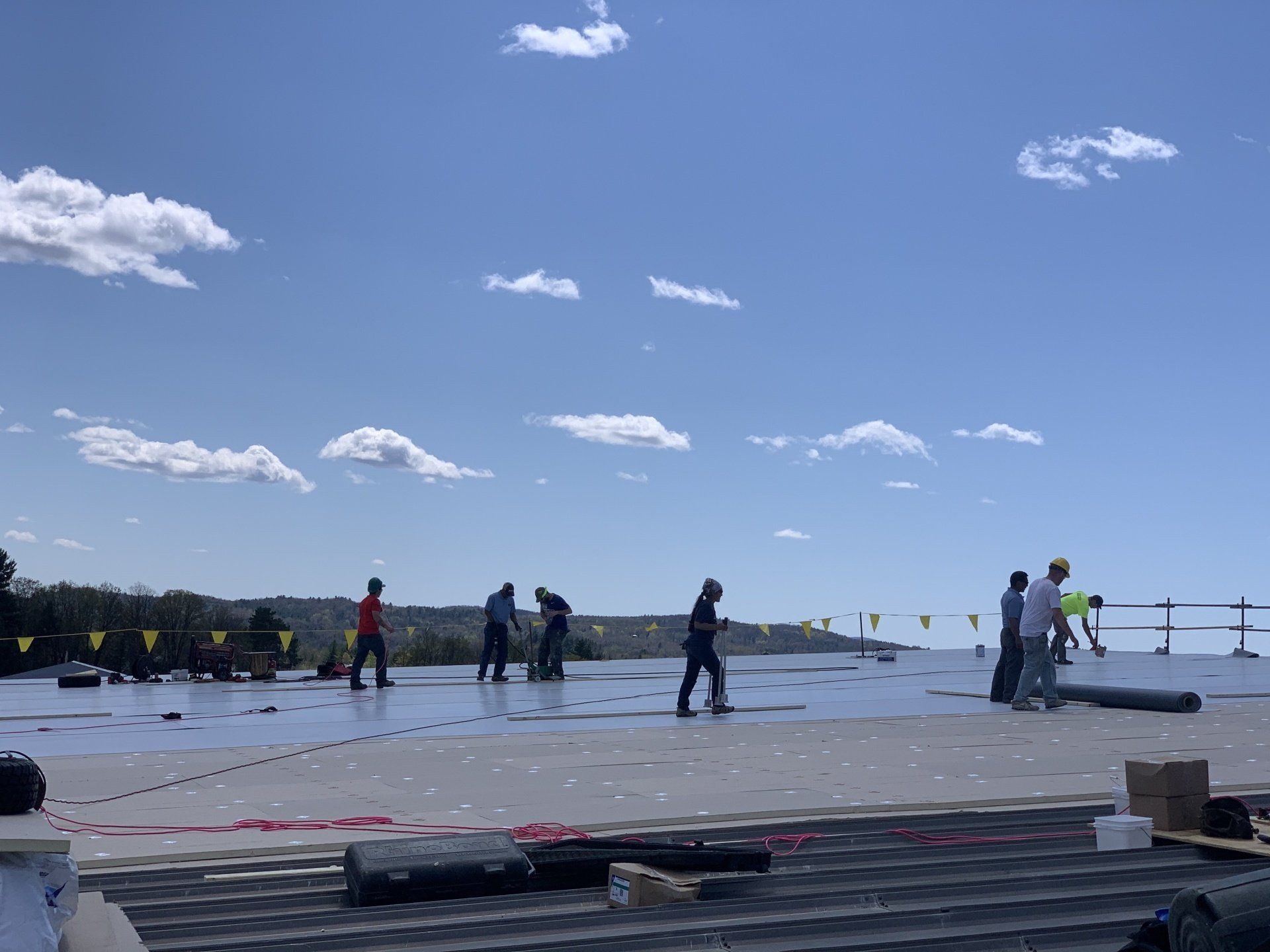 Workers on a Commercial Metal Roof Retrofit project, with materials and tools on site.