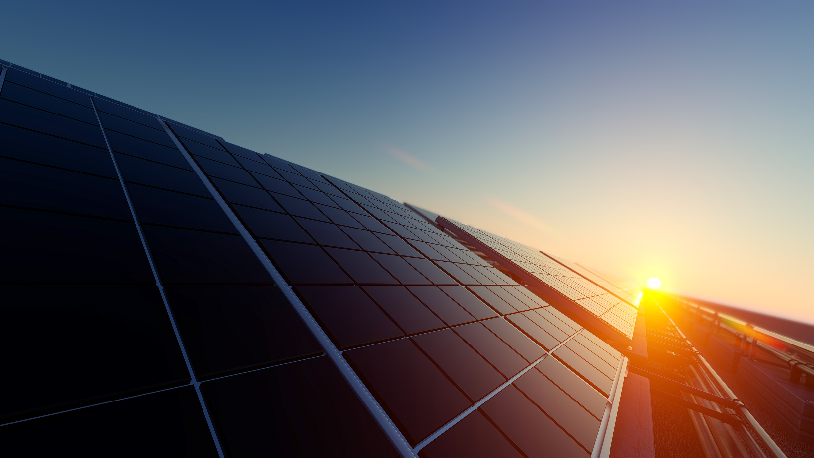 Solar panels on a roof with the sunset in the background.