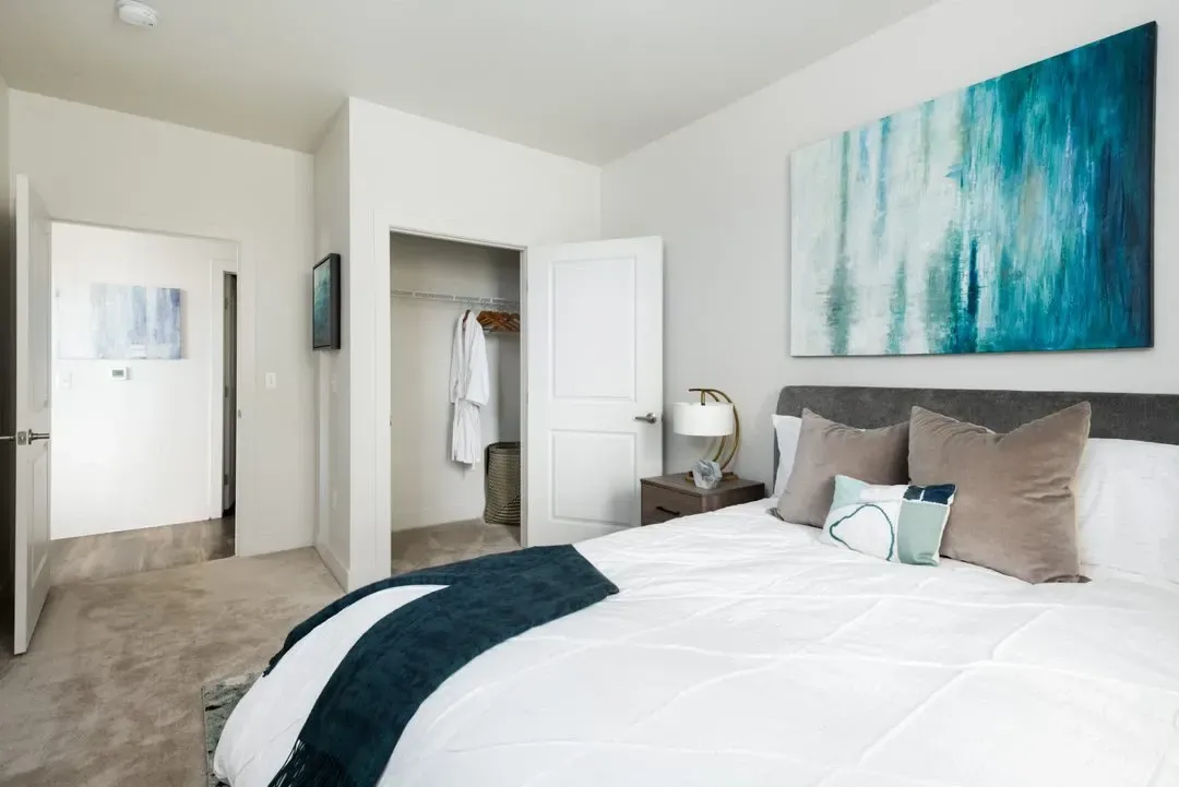 Modern bedroom with a king-size bed, walk-in closet, and abstract art.