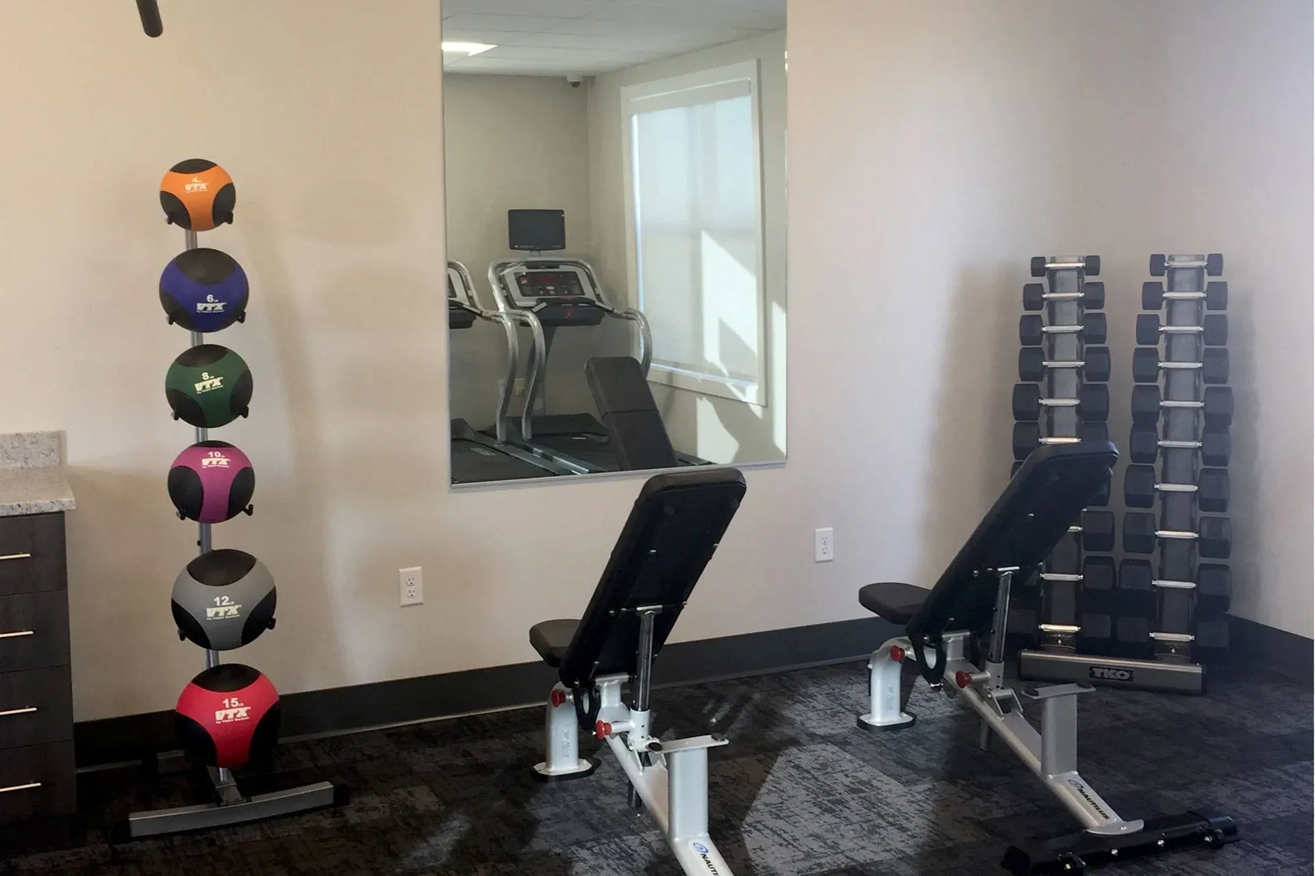 Fitness center with medicine balls, weight benches, dumbbells, and treadmills.