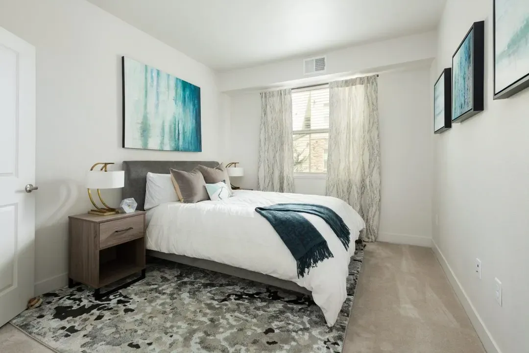 A staged bedroom with a queen-size bed, nightstand, and abstract art.