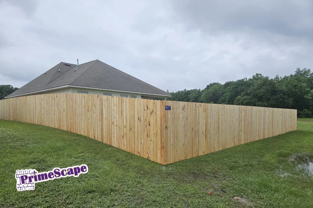 New wooden privacy fence around a house on a grassy lot under cloudy skies