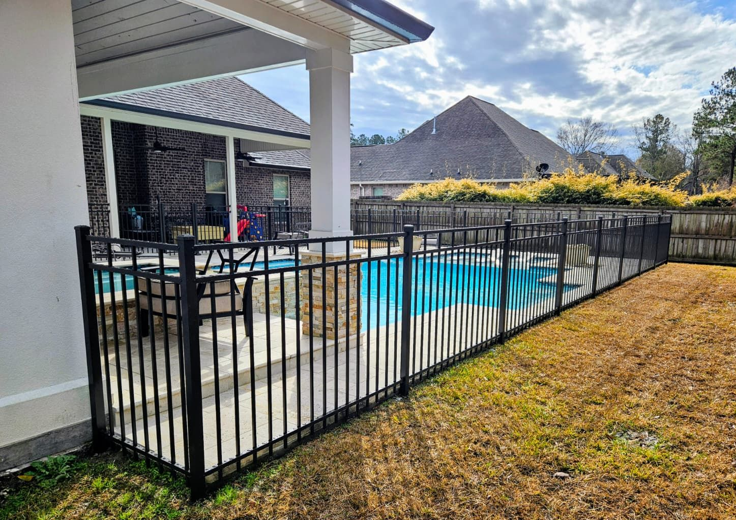 Backyard pool with black fence, patio, and pyramid-shaped mountain in the distance
