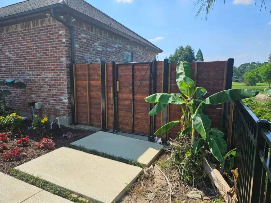 Backyard patio with two paver stepping stones, wooden fence, brick house, and banana plant