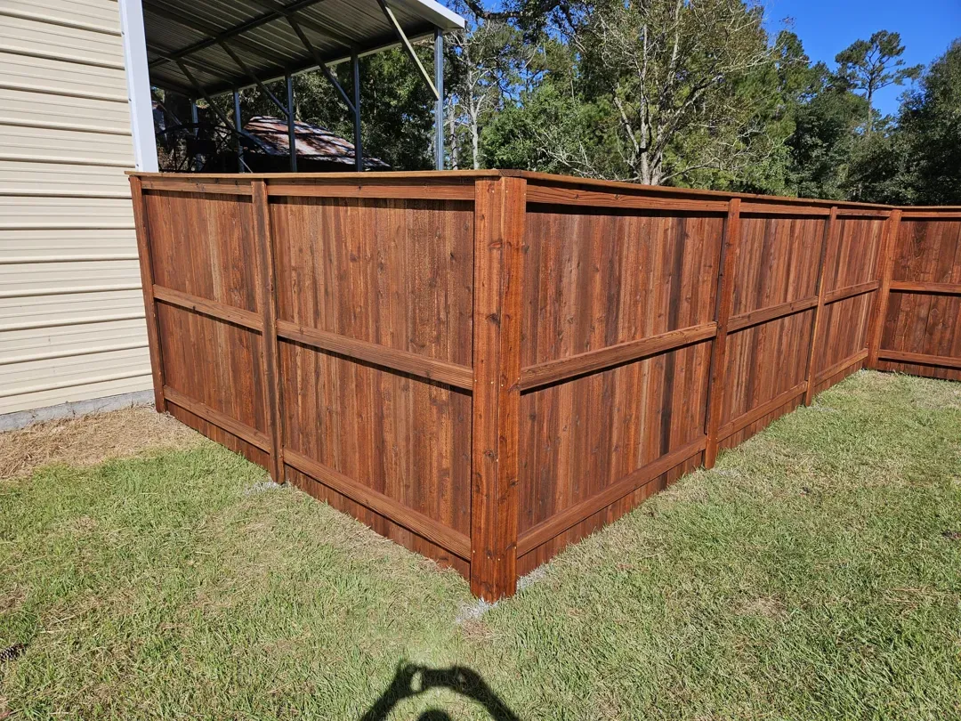 FenceWooden privacy fence enclosing a grassy yard beside a house, with a covered patio in the background
