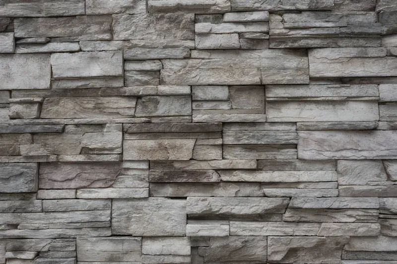Gray stacked stone wall with rough, rectangular masonry pattern