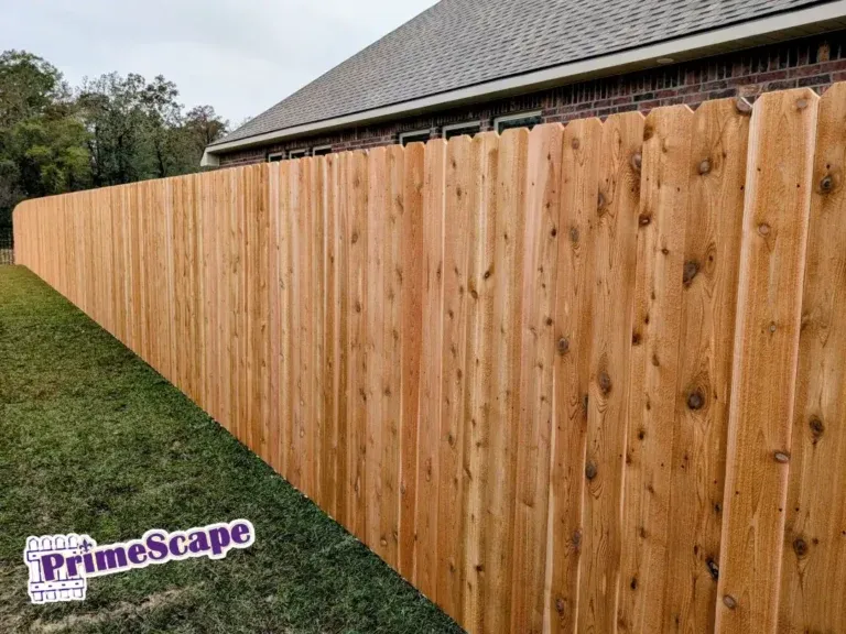 New wooden privacy fence beside a house, with a grass lawn and PrimeScape watermark