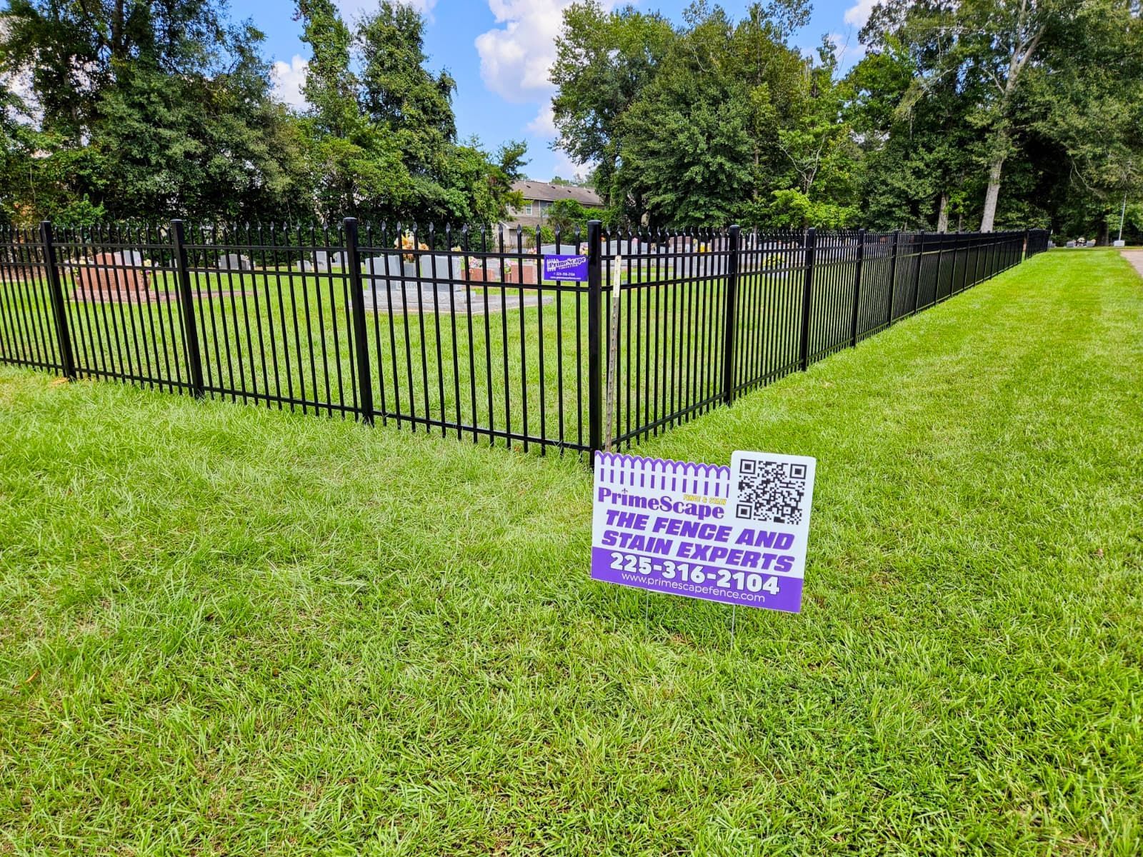 Purple protest sign on grass by black fence in a sunny park