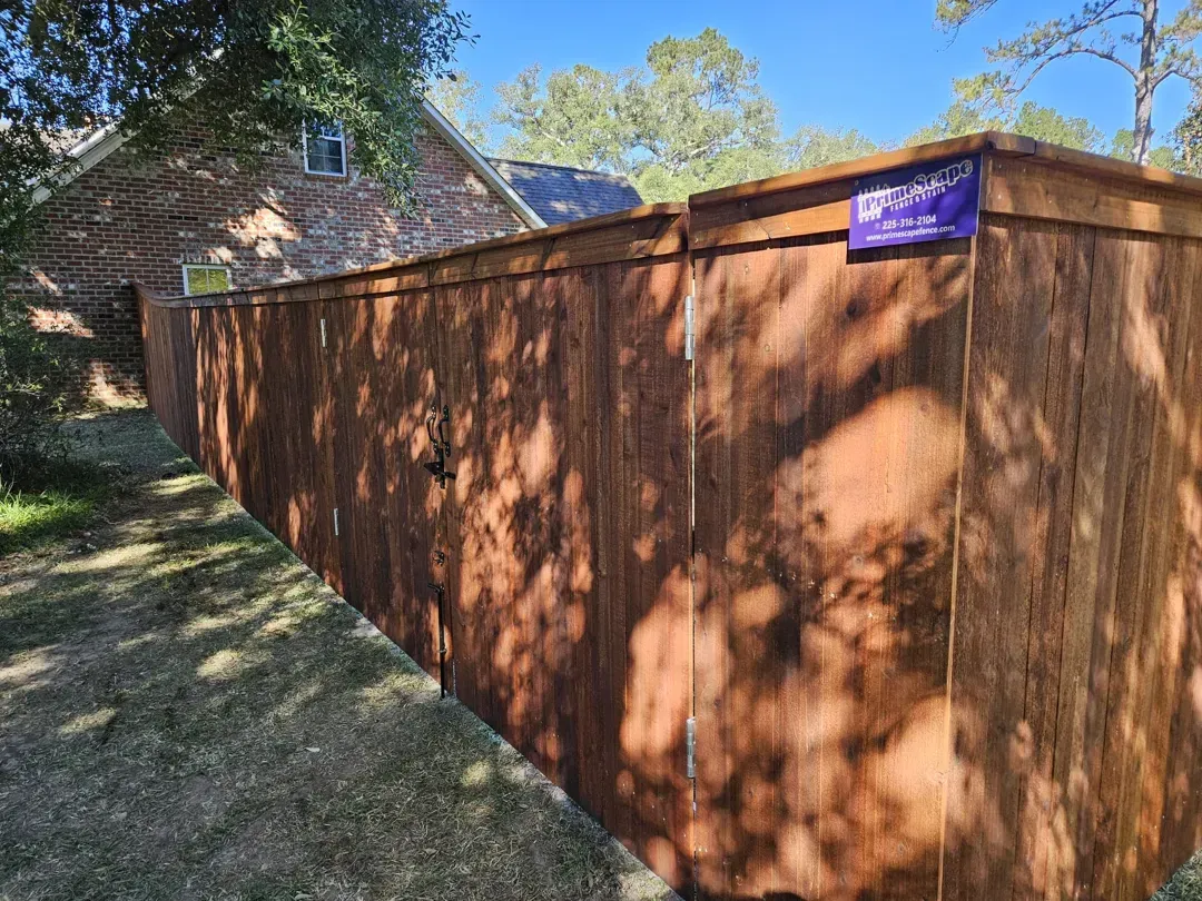 Wooden privacy fence beside a house in a sunny backyard, with a purple sign near the top.