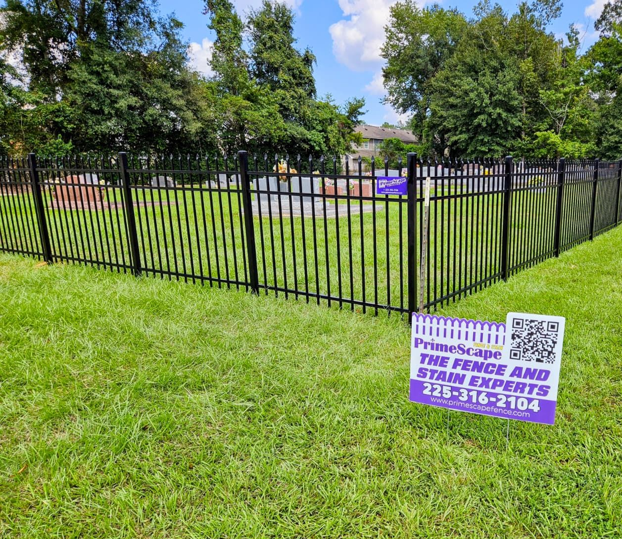 Black metal fence on grassy lawn with purple and white sign advertising a special event.