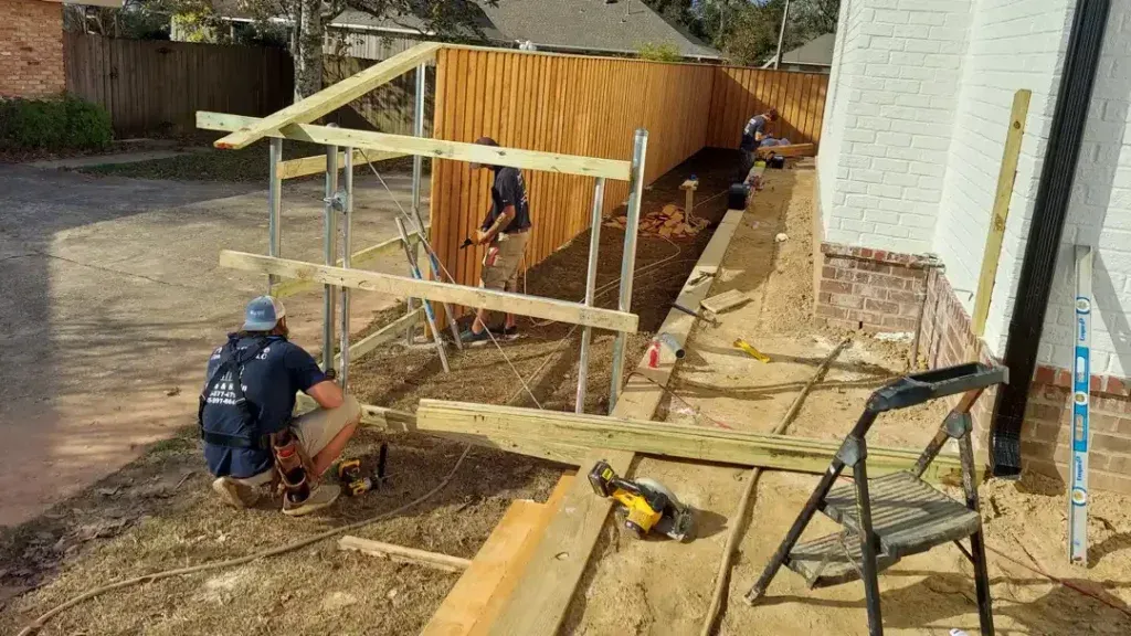 Person in a blue shirt painting a wooden fence outdoors
