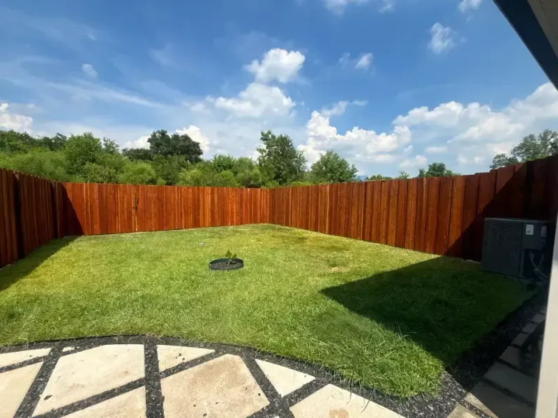 Brown wooden privacy fence around a grassy corner lot under a clear blue sky