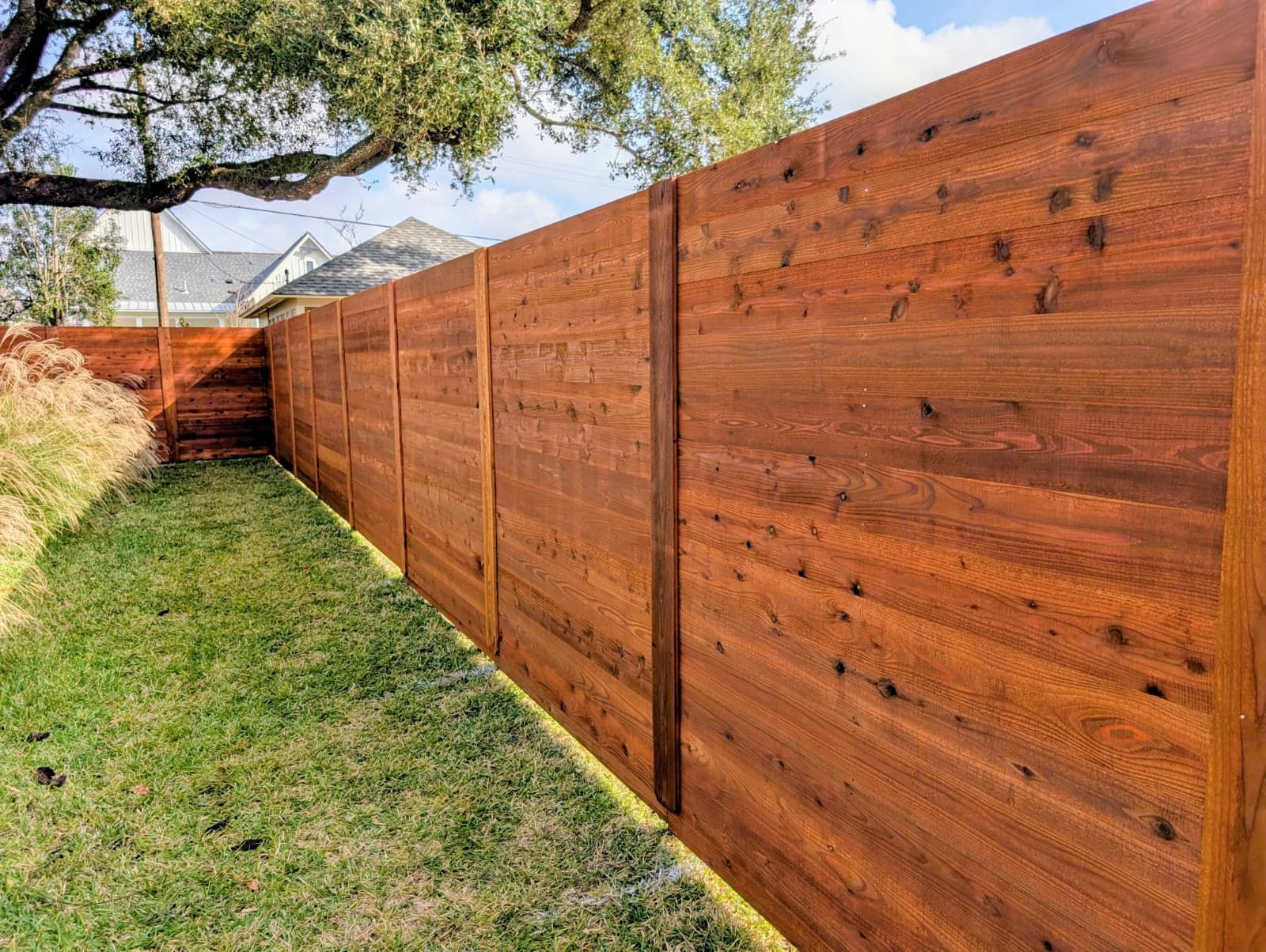 Wooden privacy fence along a grassy backyard beside a tree and distant mountains