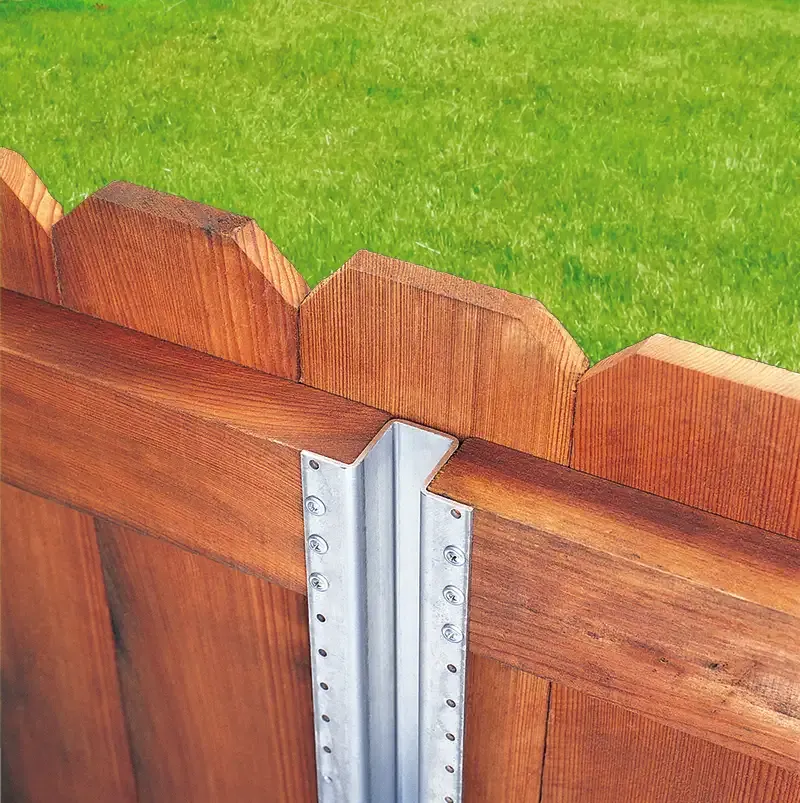 Wooden fence sections joined by a silver metal post over green grass.