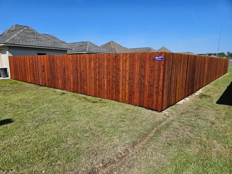 Wooden privacy fence around a grassy corner yard under a clear blue sky