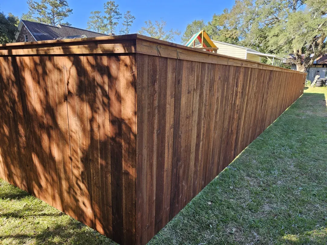 Wooden fence surrounding a grassy yard under a clear blue sky