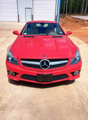 Red Mercedes-Benz coupe parked on a driveway in front of a garage