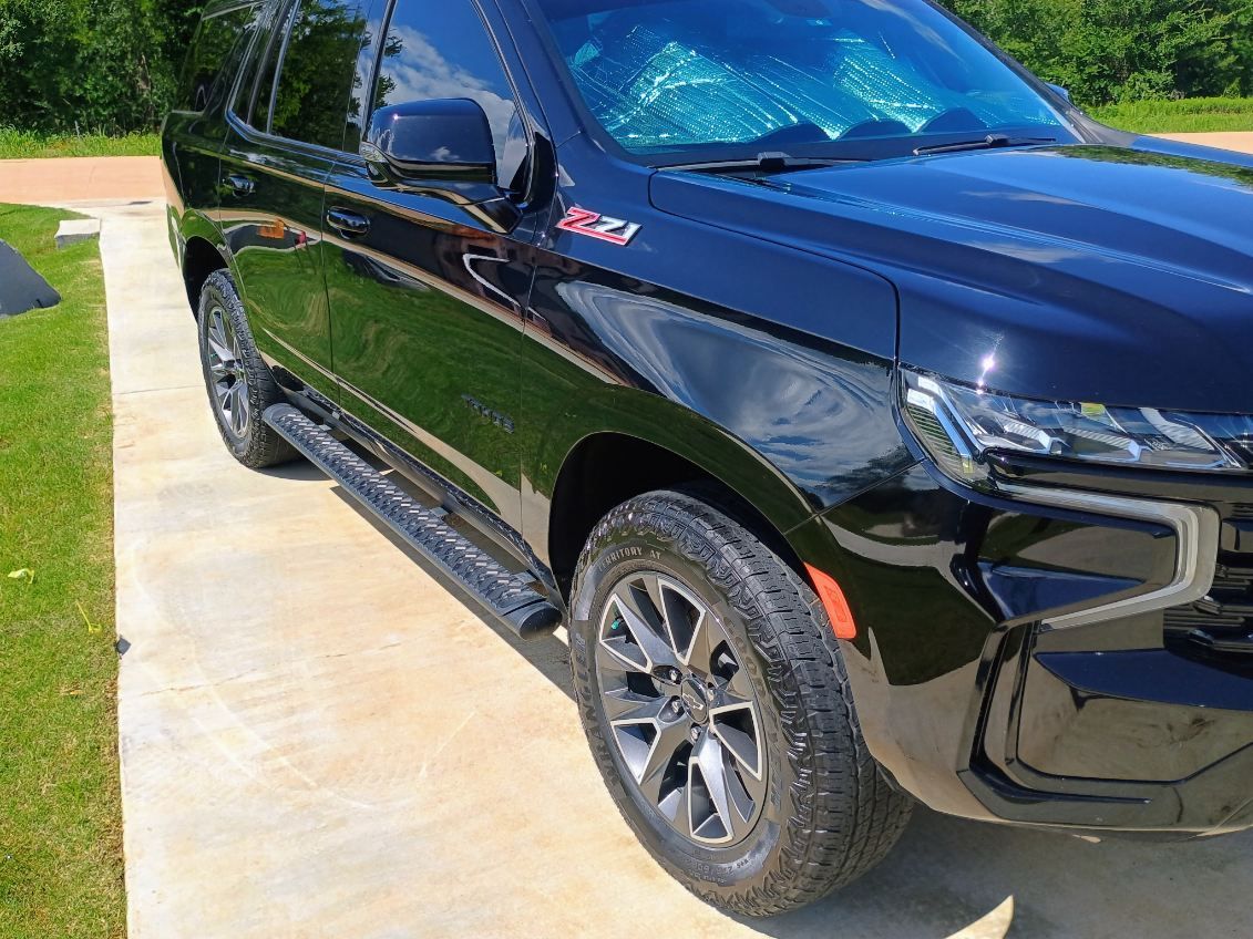 Black pickup truck parked on a sunny driveway, front side view